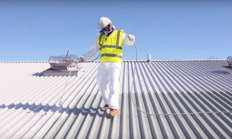 Operative spraying a reflective coating onto a metal roof